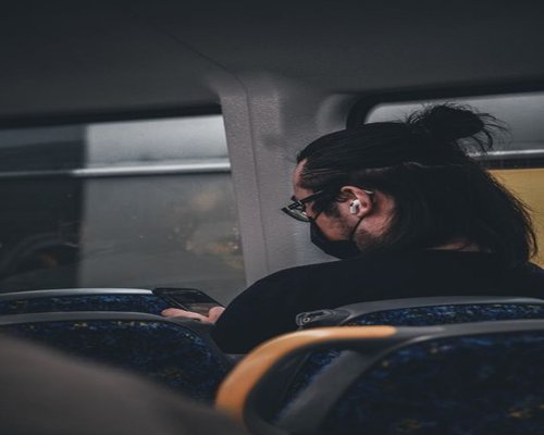 Person holding a phone while sitting inside a public transit bus